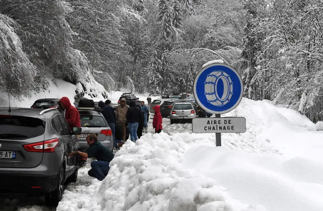 People in a layby in the Alps fitting snow chains